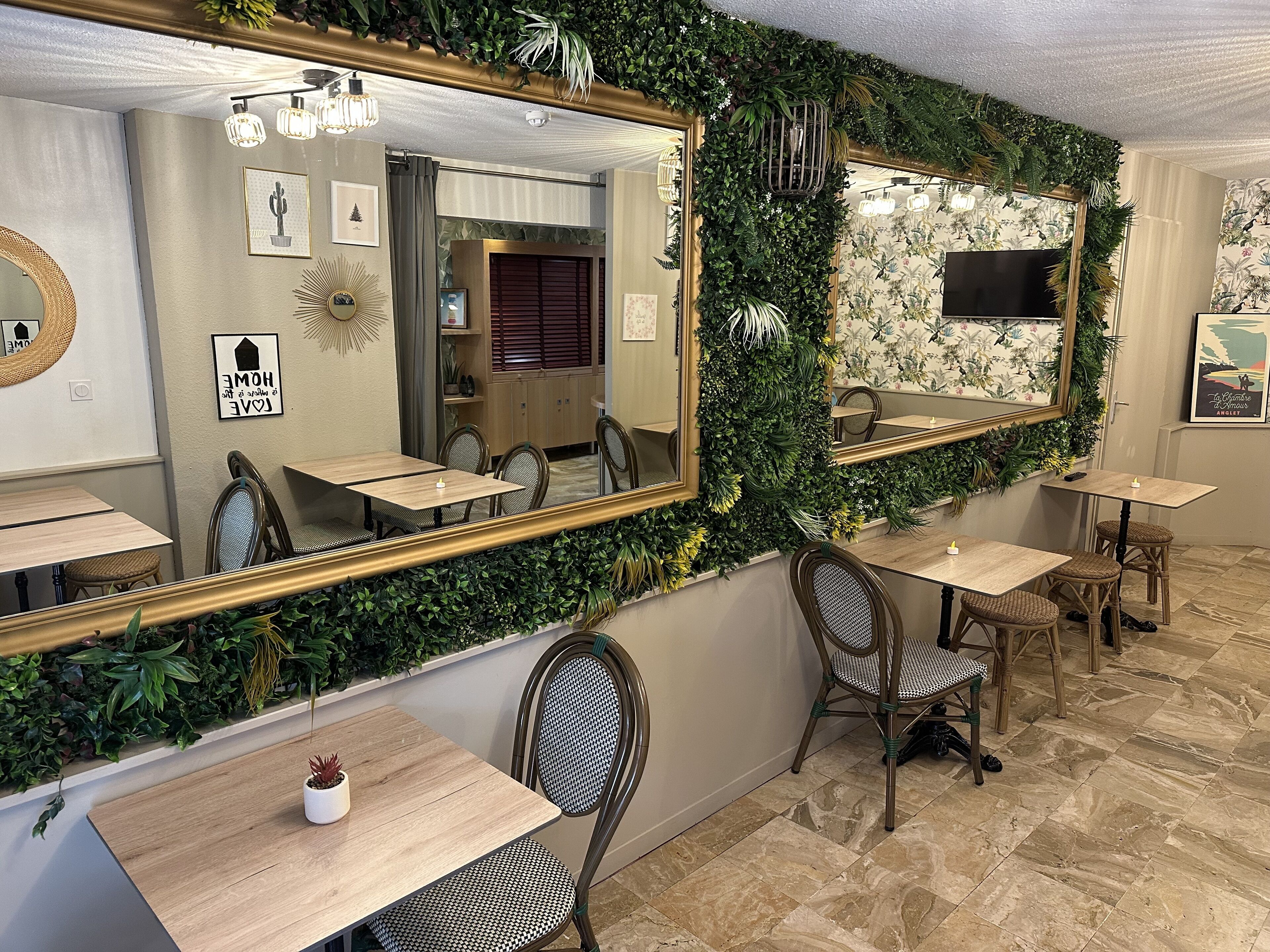 Ein Restaurant mit Spiegelwand, Holztischen, Korbstühlen und Fliesenboden.