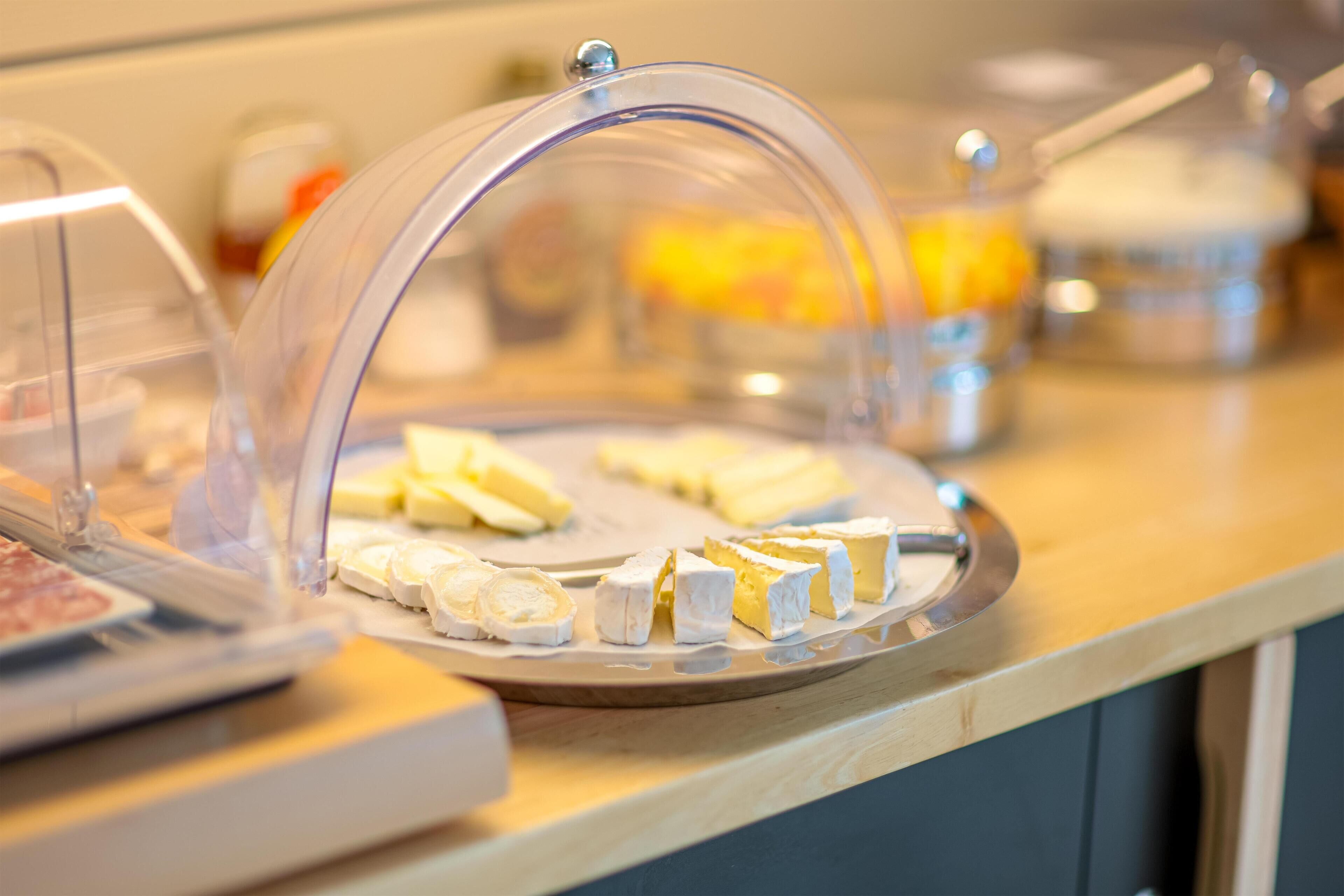 A cheese display with a transparent dome cover on a wooden counter.