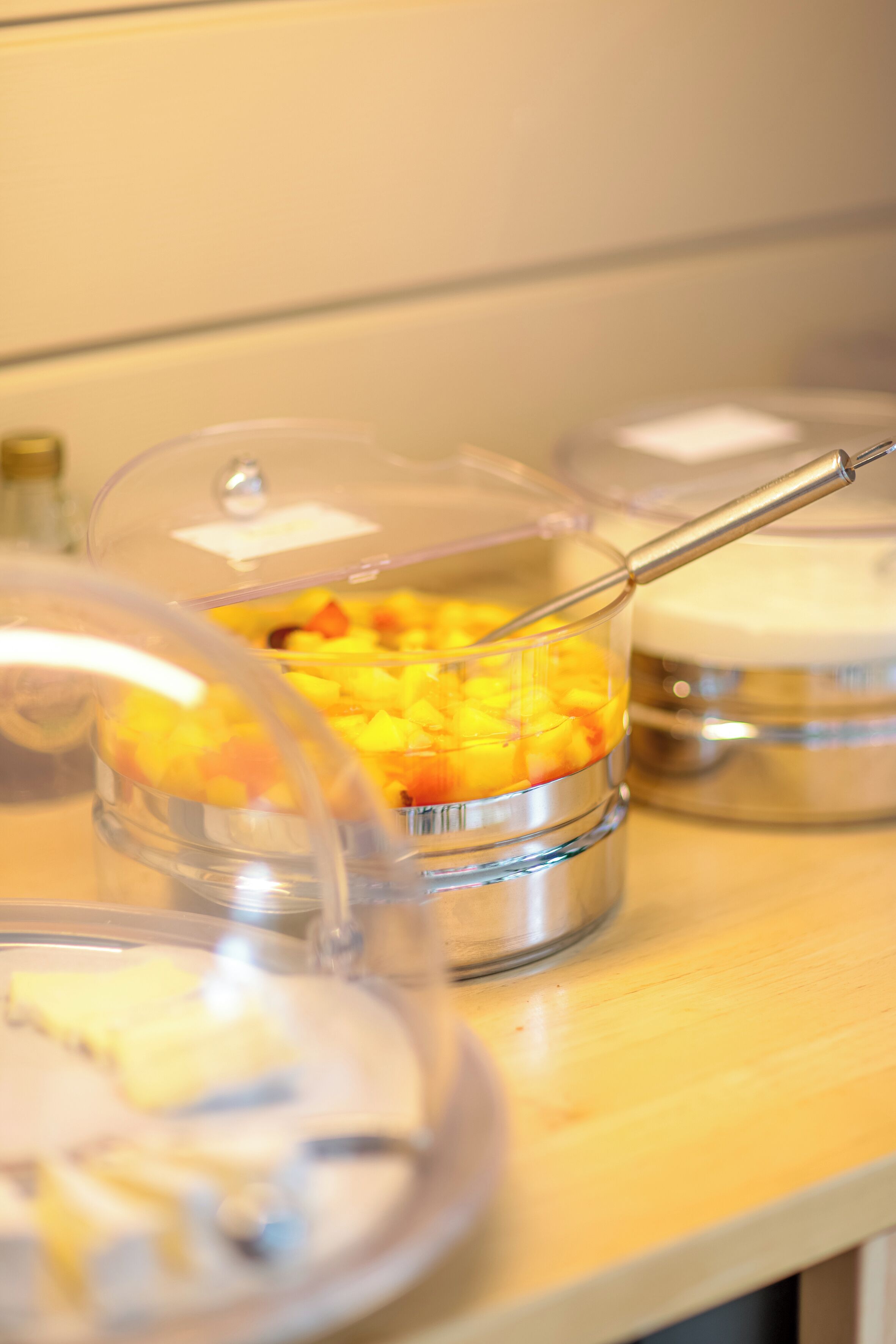 A buffet setup with covered food containers on a wooden table.