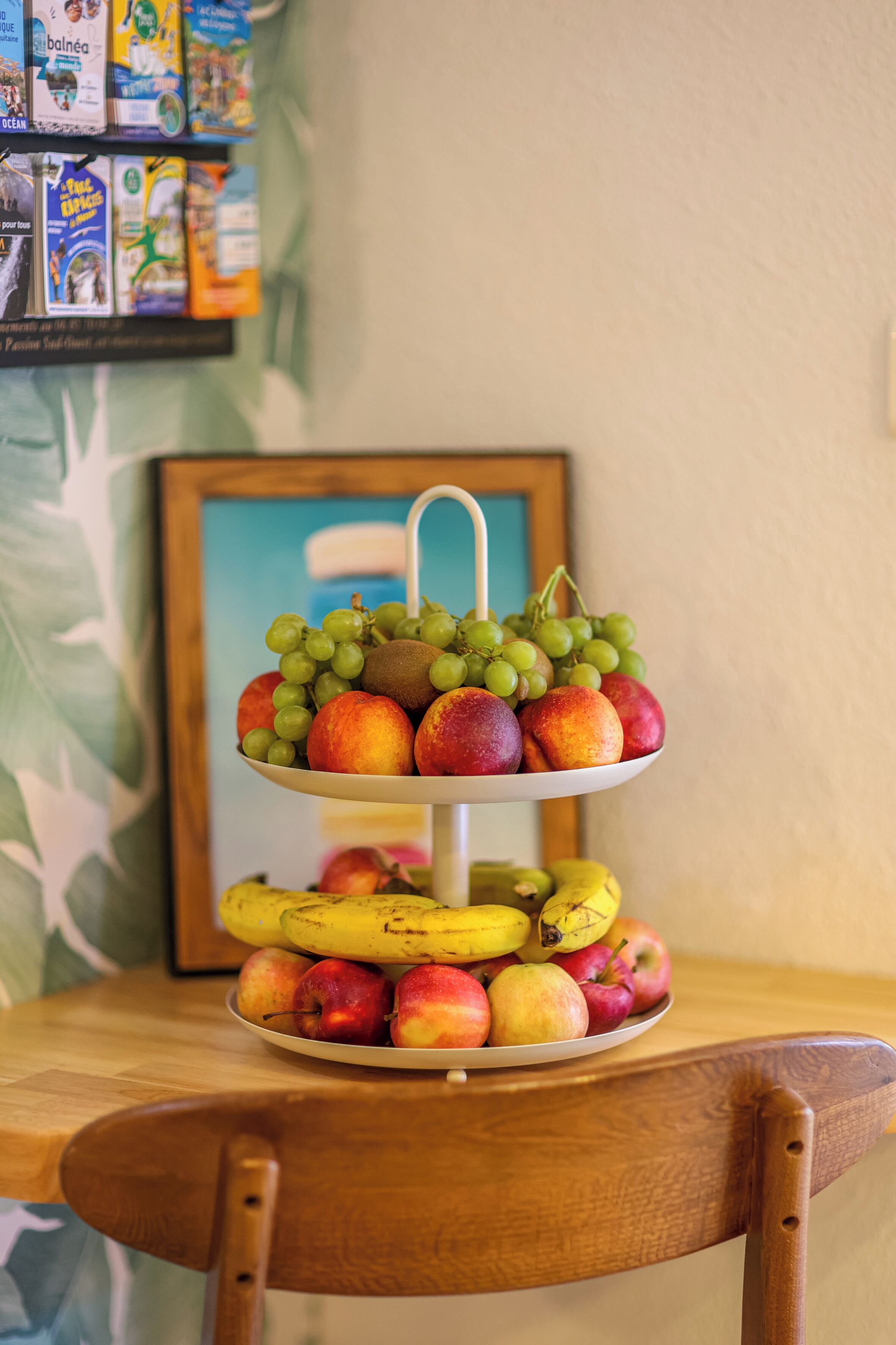 A fruit stand with apples, bananas, grapes, and peaches on a wooden table.