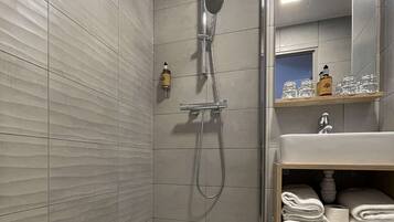 Une salle de bain moderne avec une douche, un lavabo et un miroir.