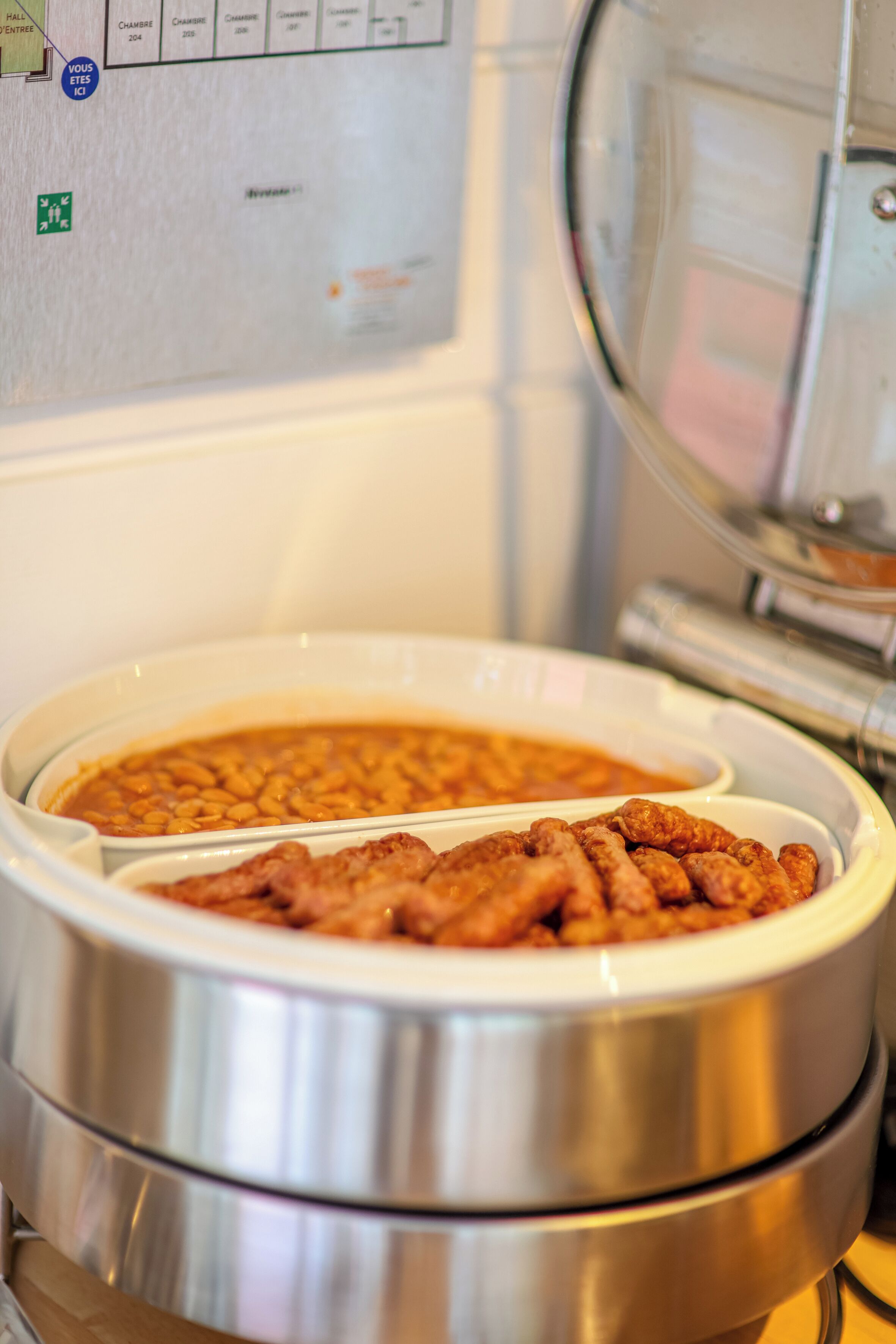 A buffet setup with two bowls of food, one containing beans and the other containing meat.