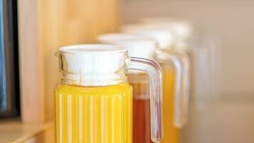 A stainless steel kitchen counter with a glass pitcher filled with a yellow liquid, likely juice or tea, and a matching glass pitcher in the background.