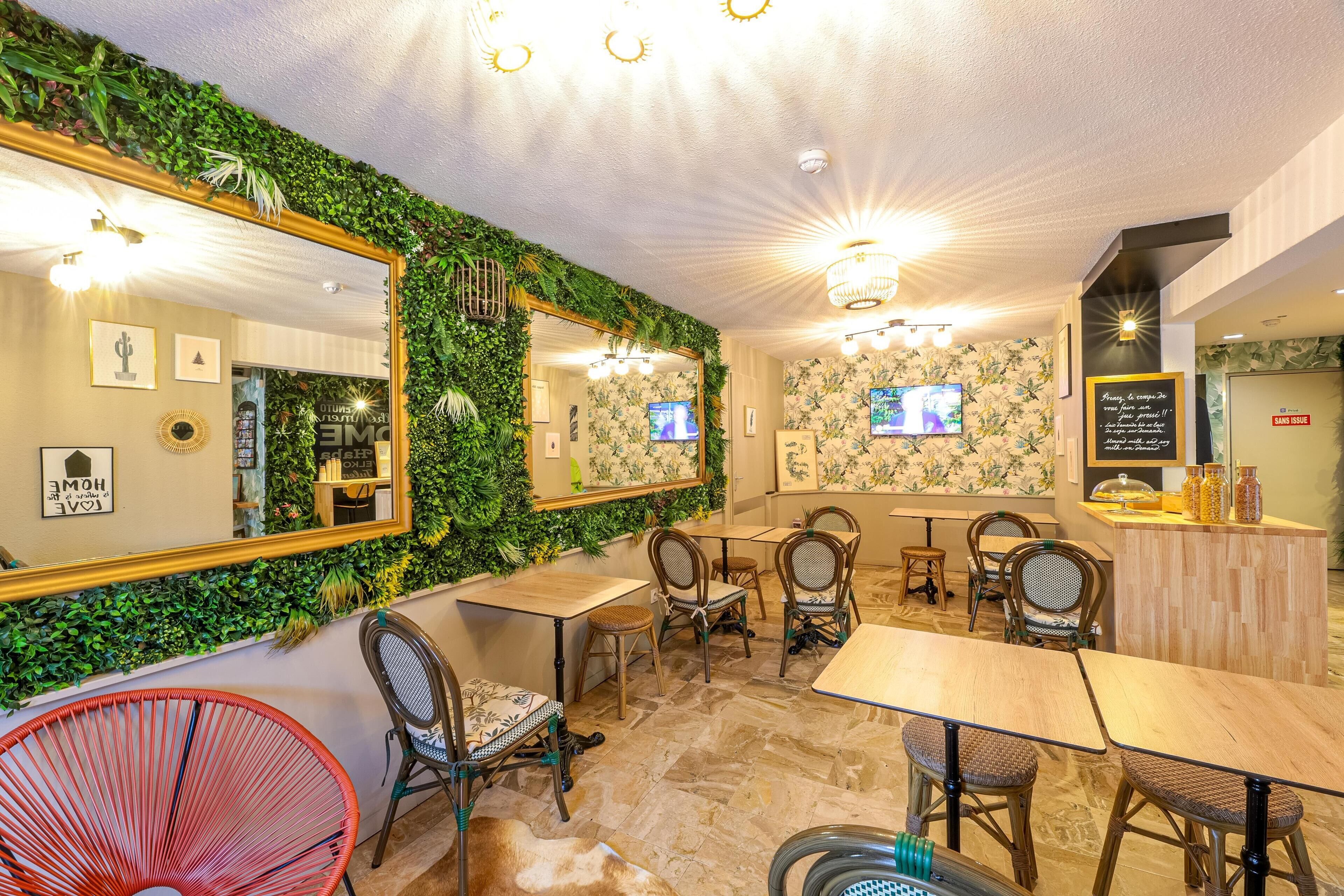 A restaurant with a green wall, multiple tables and chairs, and a mirror.