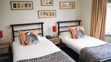 Ein Hotelzimmer mit zwei Betten, jedes mit einem Zebra-Kissen, einem Nachttisch mit Lampe und gerahmten Bildern an der Wand.