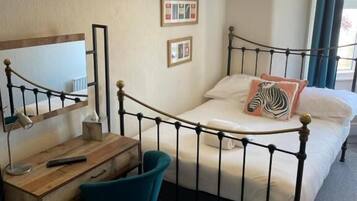 Ein Schlafzimmer mit Bett, Schreibtisch, Stuhl und einer Hängelampe.