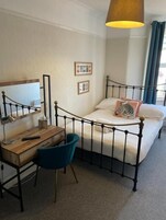 Un dormitorio con cama, escritorio, silla y lámpara colgante.