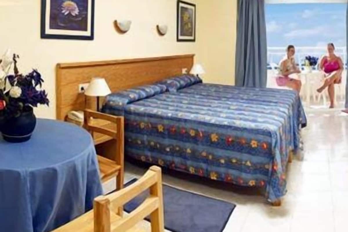 Quarto de hotel com uma cama, uma cadeira, uma mesa e vista para o mar.