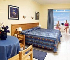 Una habitación de hotel con cama, una silla, una mesa y vista al mar.