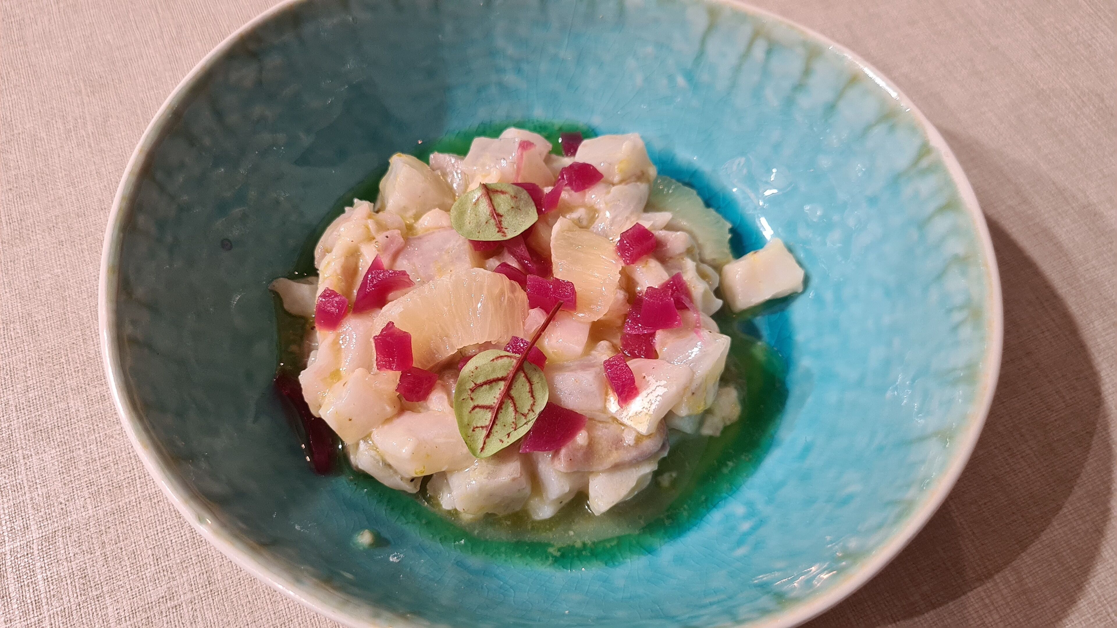 A bowl of ceviche with diced fish and red onions.