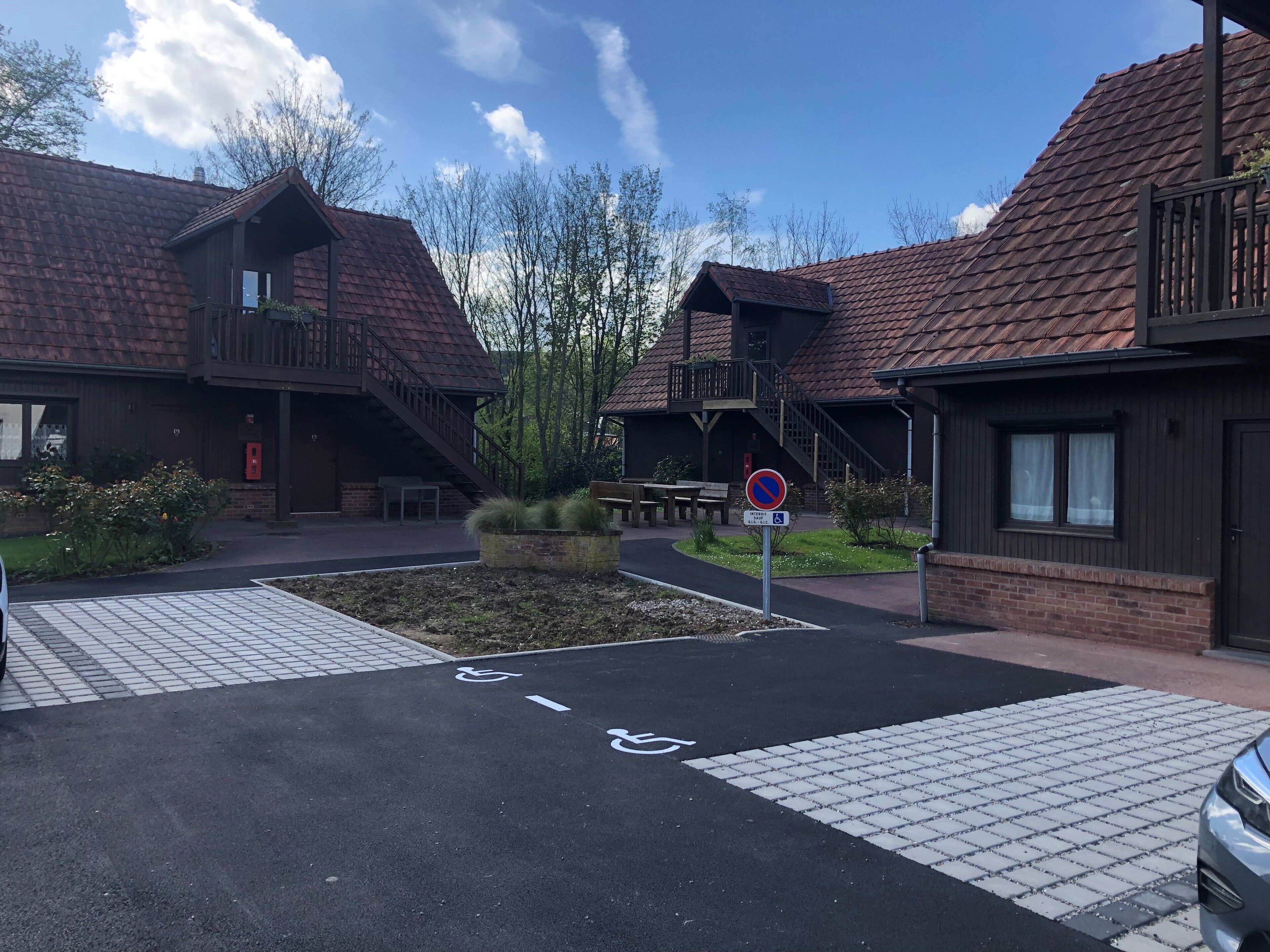 A residential building with a brick facade, a wheelchair-accessible ramp, and a no parking sign.
