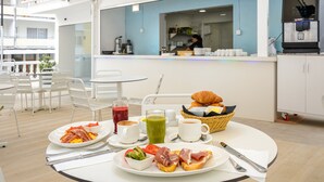 A breakfast setting with plates of food, a coffee machine, and a buffet area in the background. - Hotel Vibra Lei Ibiza (Ibiza Town)