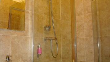 A bathroom with a shower, a sink, and a mirror.