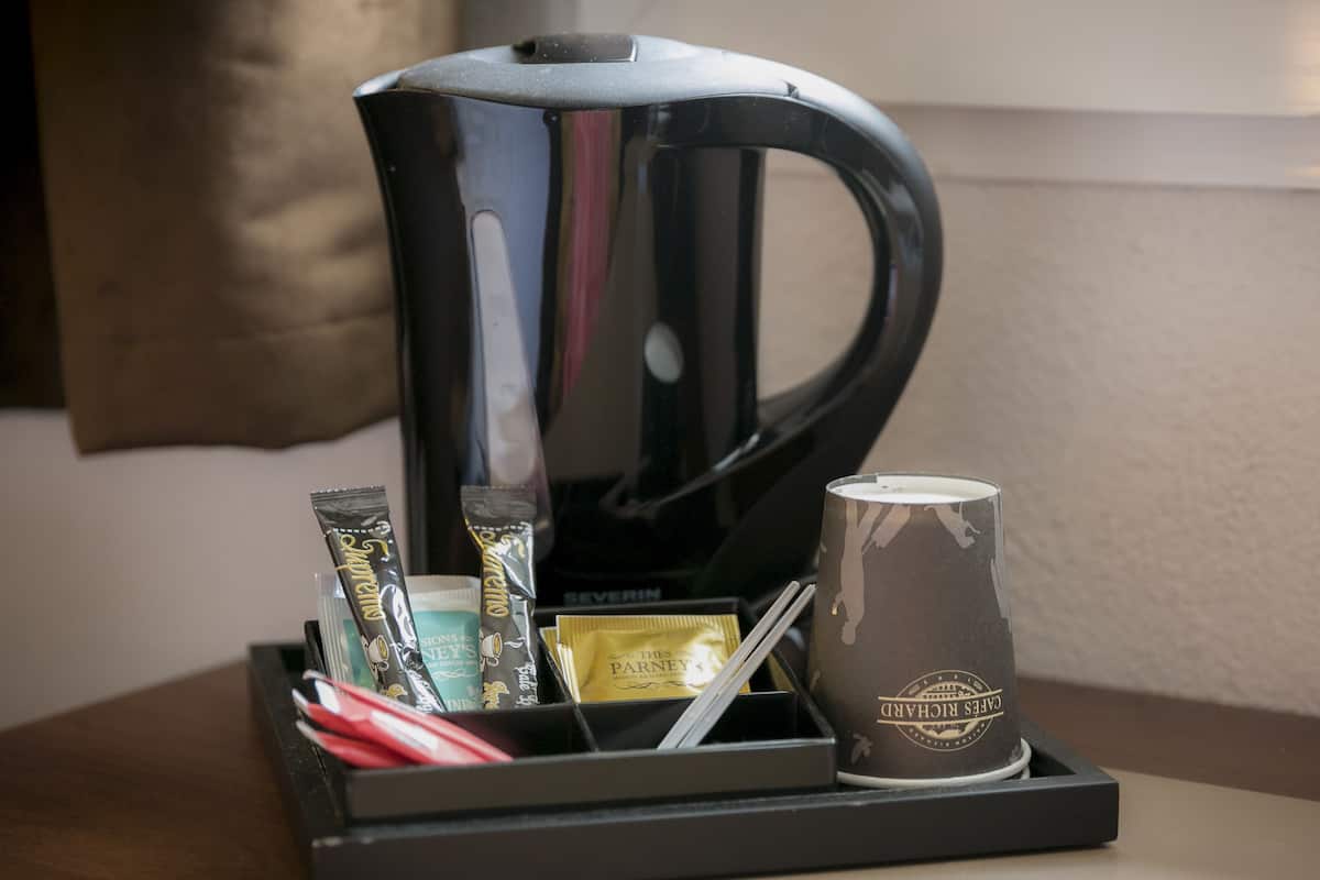 A coffee maker, a mug, and a tray with various items including a tube of toothpaste and a packet of coffee.