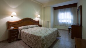Un dormitorio con una cama de madera, dos lámparas de noche, una mesita de noche, un escritorio y una silla.