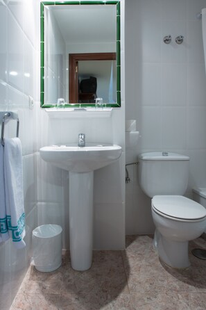 A bathroom with a pedestal sink, toilet, and a mirror with a green frame. - Hotel Riviera (Córdoba)