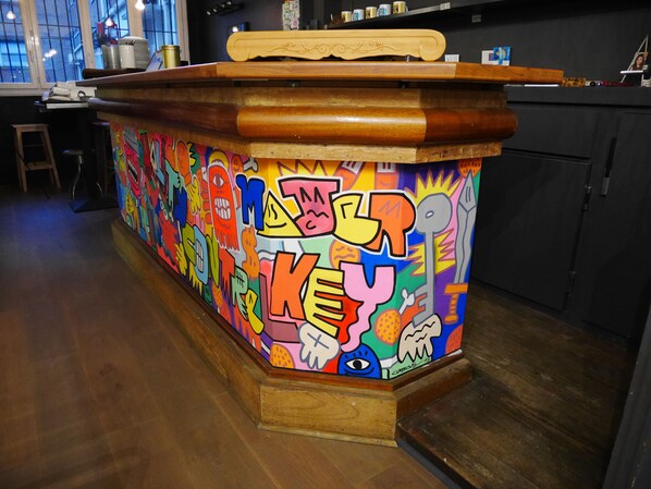 A colorful bar area with a wooden counter and a vibrant mural.