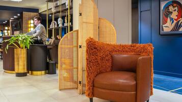 A reception area with a counter, a plant, a decorative chair, and a partition with a woven design.