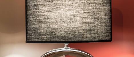A modern lamp with a metallic base and a rectangular shade on a wooden surface.