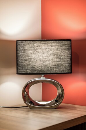 A modern lamp with a metallic base and a rectangular shade on a wooden surface.