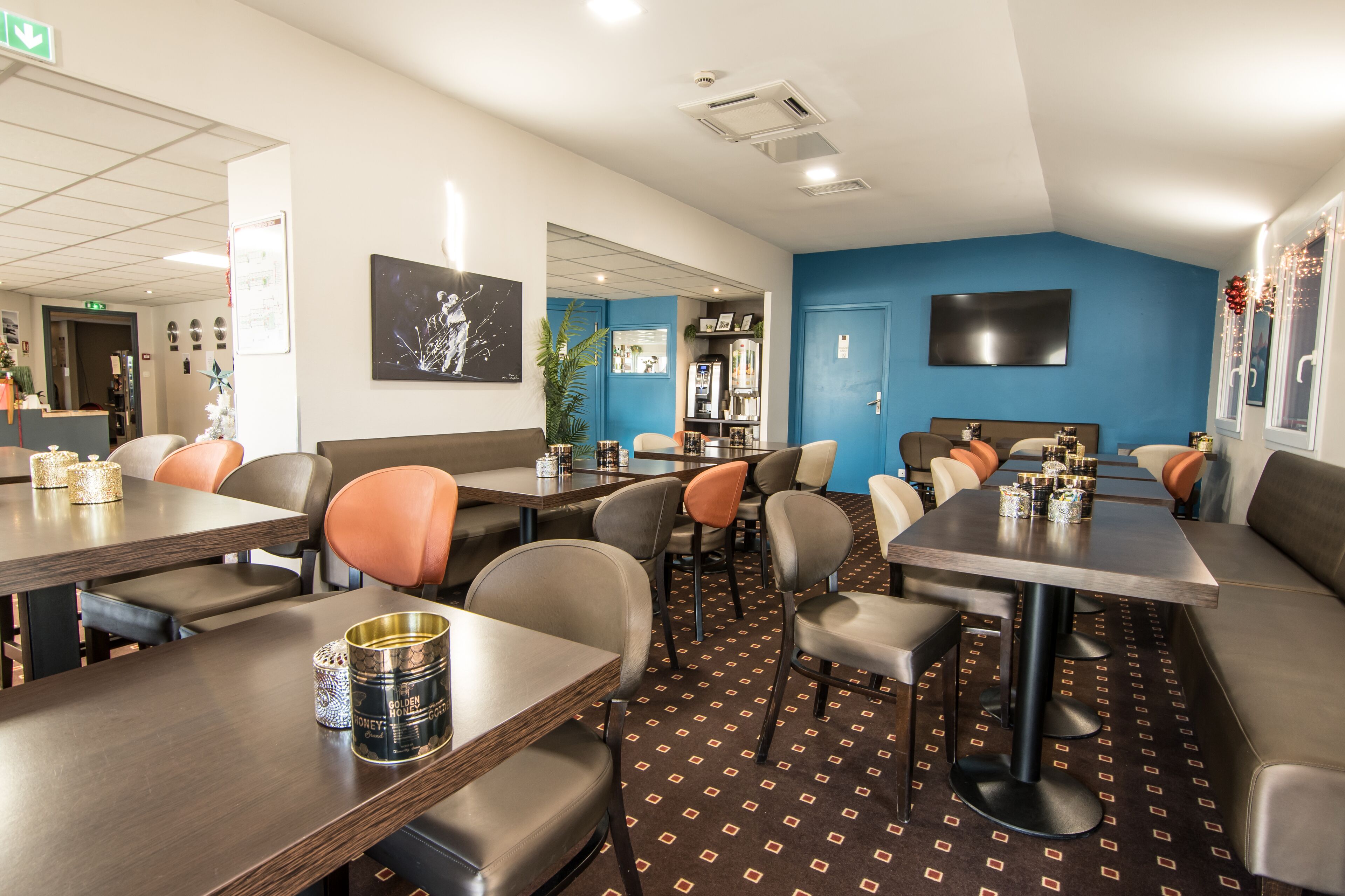 Un restaurante con cabinas y mesas, una pared de acento azul y un televisor de pantalla plana.