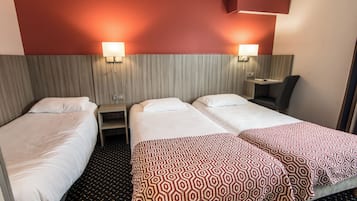 Ein Hotelzimmer mit zwei Einzelbetten, einem kleinen Schreibtisch, einem Stuhl und einem Nachttisch.