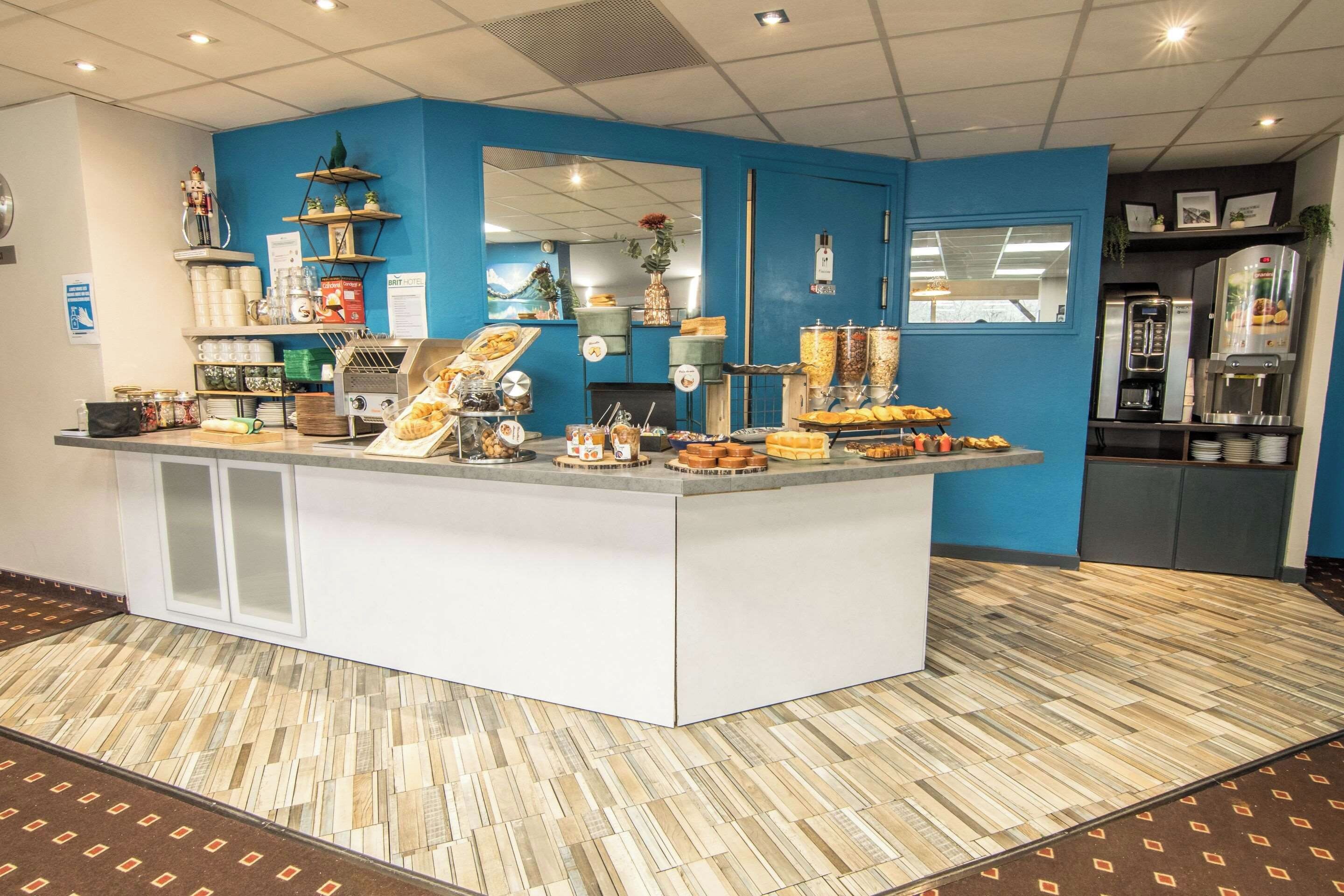 Zona de desayuno tipo buffet con diferentes opciones de comida y una máquina de café.
