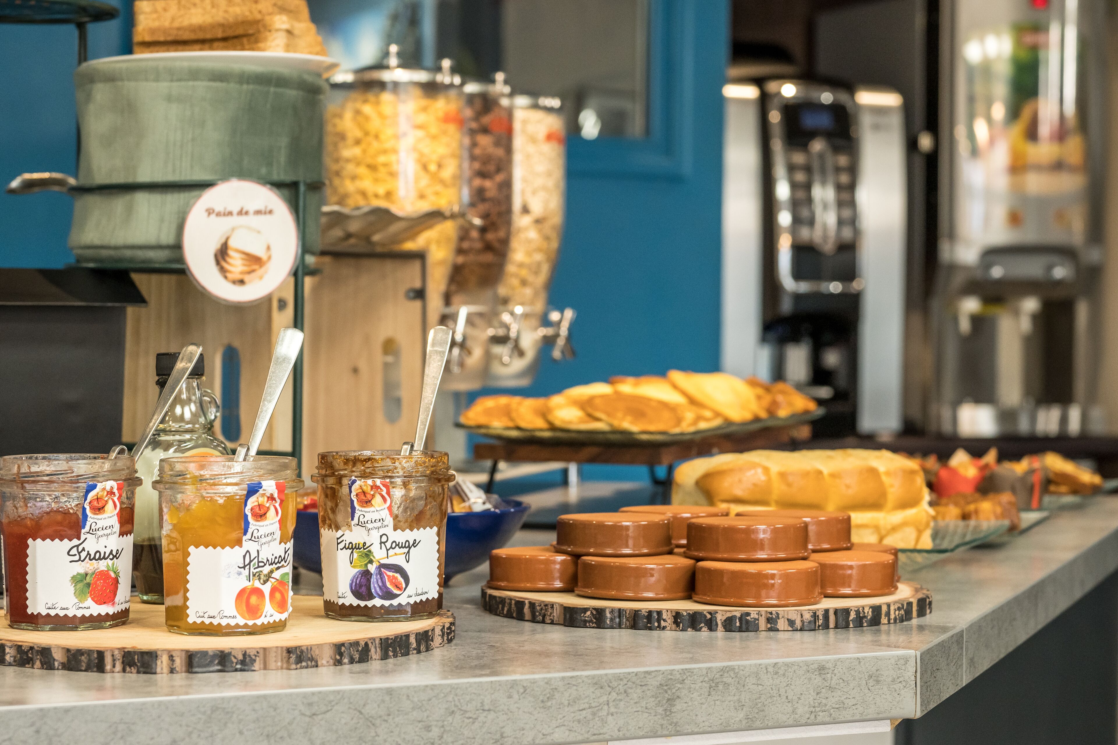 Un buffet de petit-déjeuner proposant un assortiment de confitures, de viennoiseries et une machine à café.