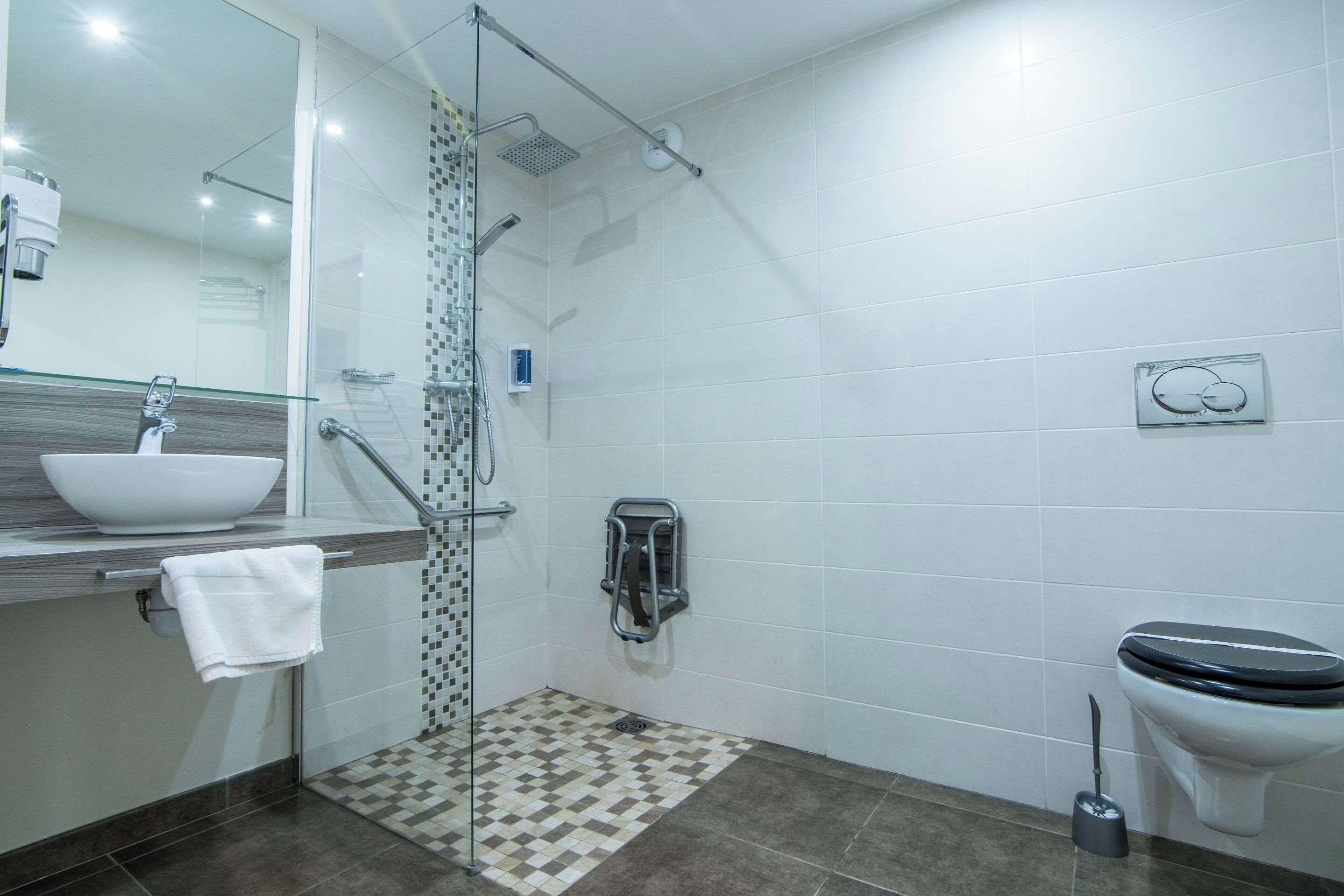 A modern bathroom with a glass shower enclosure, a sink with a mirror, and a toilet.