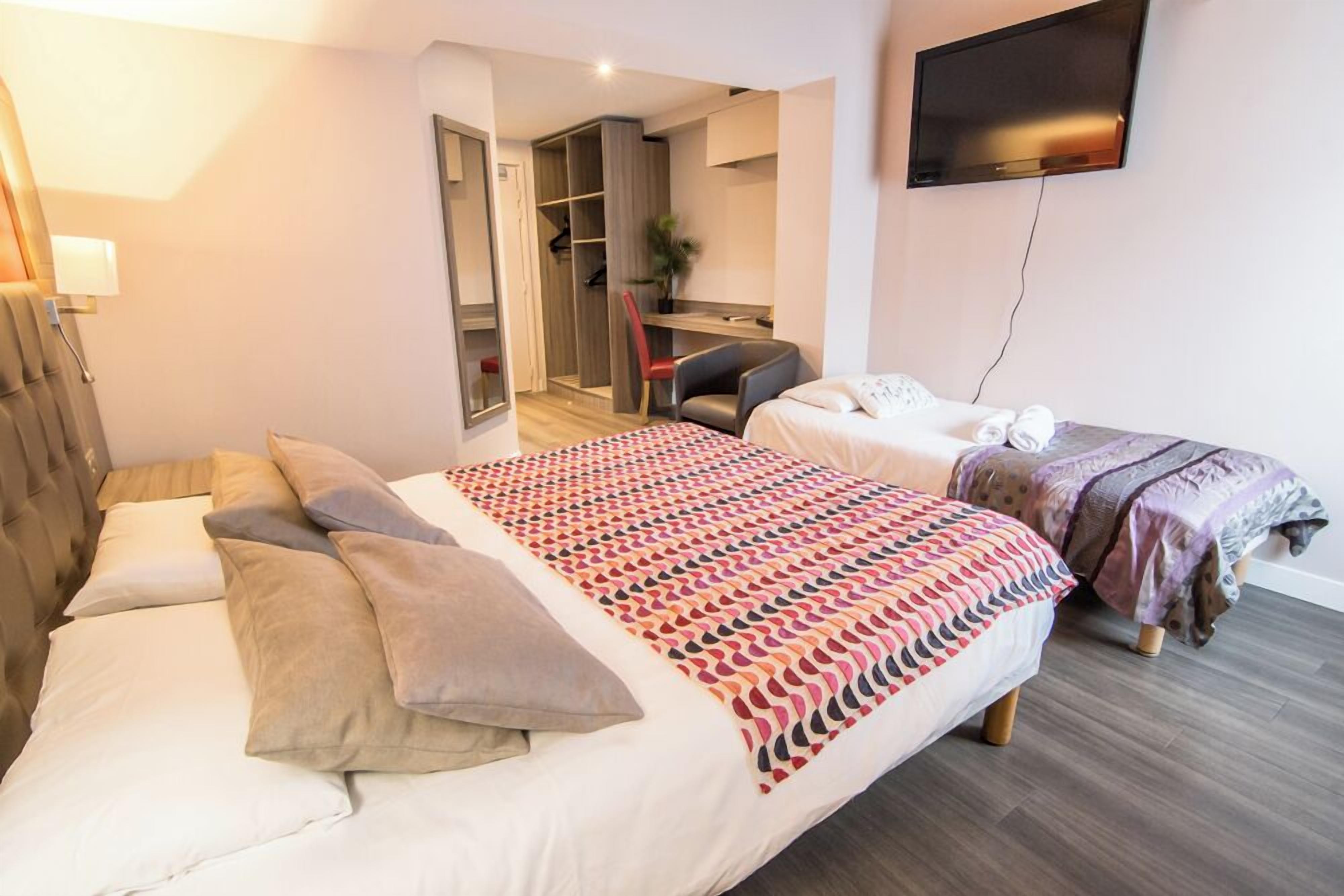 Ein Hotelzimmer mit Bett, Schreibtisch, Stuhl und Fernseher.