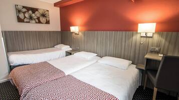 A hotel room with two beds, a desk, and a chair. There are wall-mounted lamps and a painting of flowers.