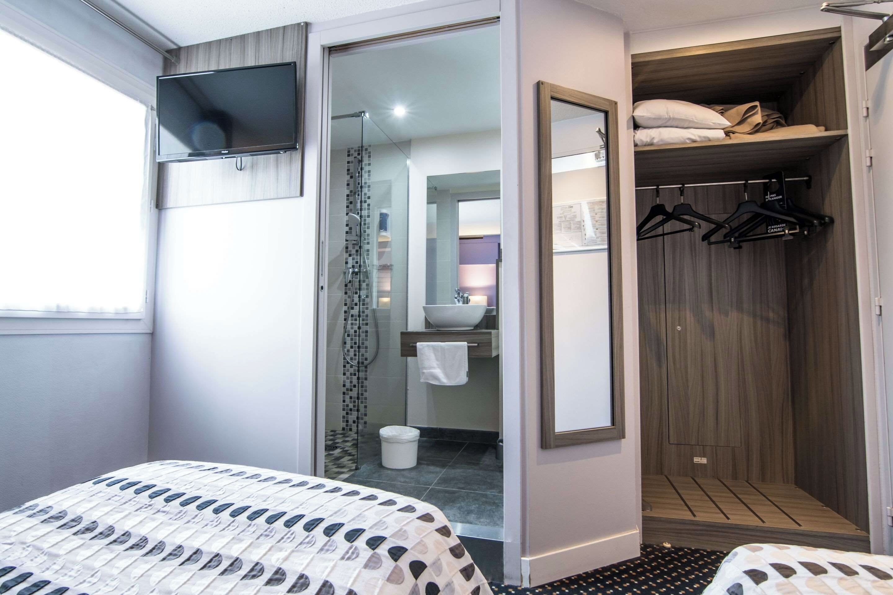 Ein Hotelzimmer mit Bett, Kleiderschrank, Spiegel und Fernseher.
