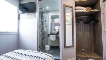 A hotel room with a bed, a wardrobe, a mirror, and a television.