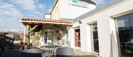 Um hotel com área de pátio, mobiliário de área externa e uma placa com a inscrição "BRIT HOTEL Comfort".