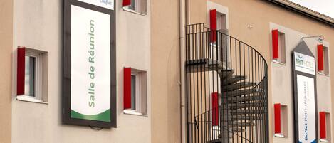 Exterior de un hotel con un letrero del BRIT HOTEL y un letrero que indica el Buffet Petit-déjeuner à volière.