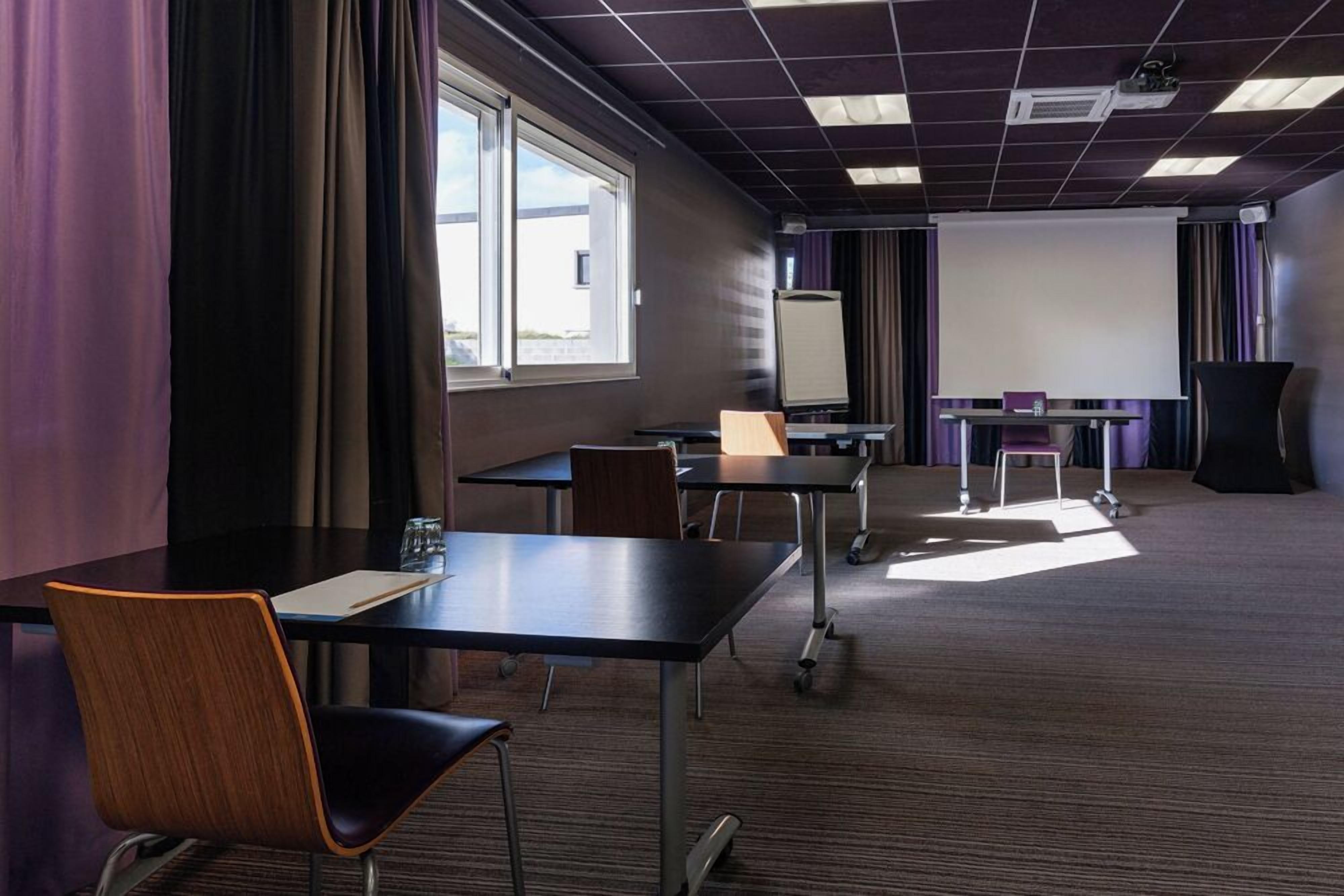 A conference room with tables, chairs, a projector, and a whiteboard.