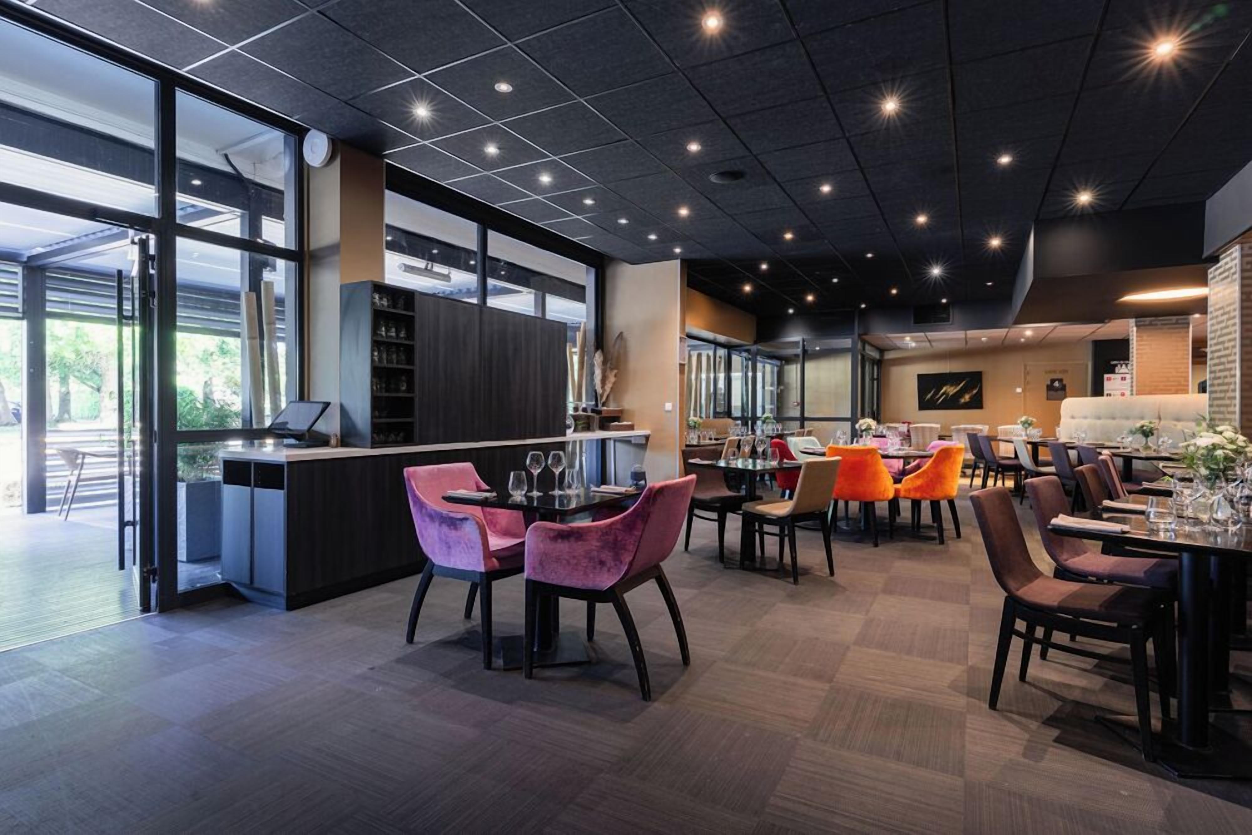 A modern restaurant with a bar area, dining tables with chairs, and a view of the outdoors.
