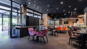 A modern restaurant with a bar area, dining tables with chairs, and a view of the outdoors.