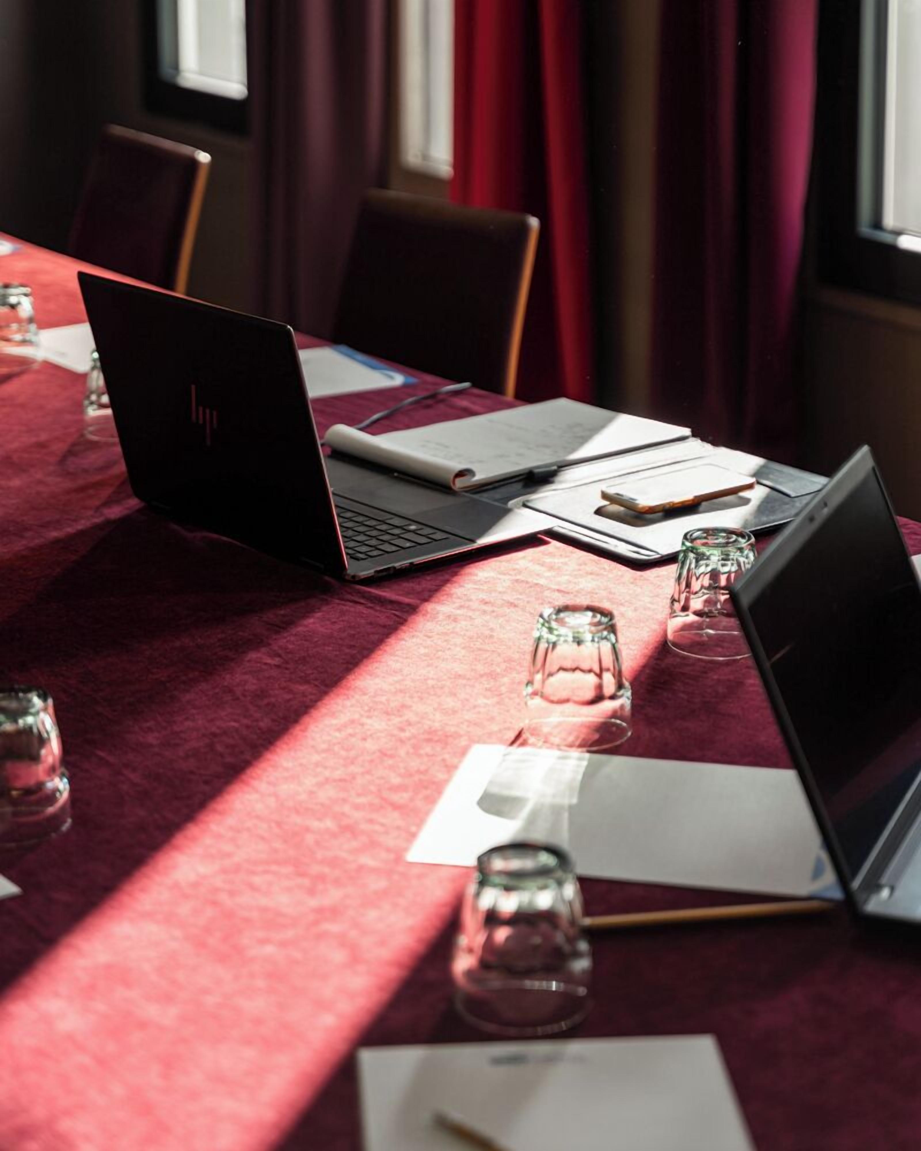 A conference table with laptops, documents, and glassware.