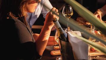 Un couple est assis à une table dans un restaurant, avec une bouteille de vin et un verre devant eux.
