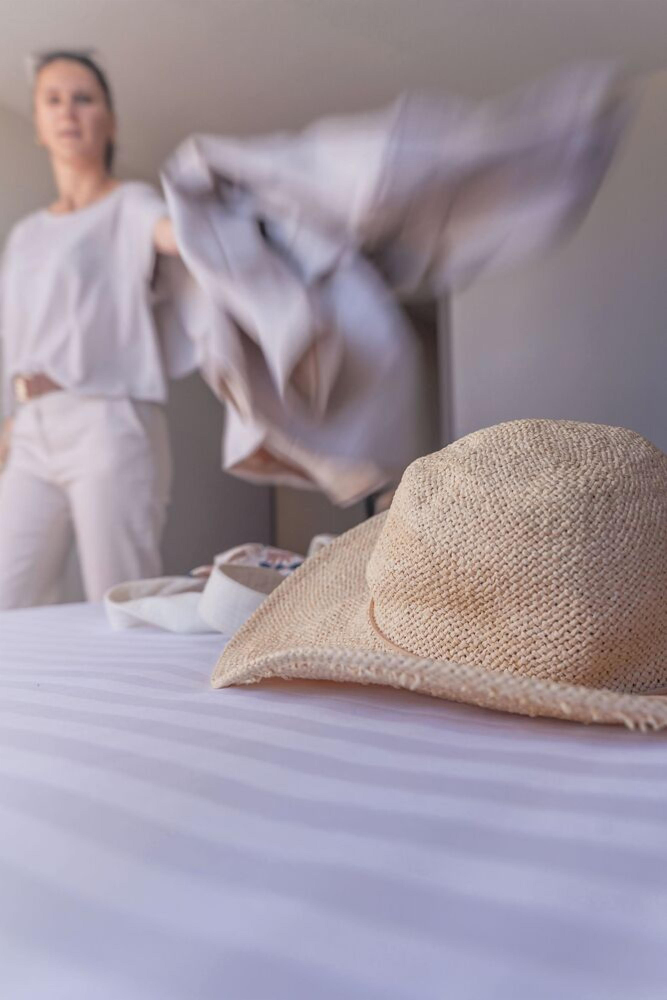 A bed with a straw hat and a white pillow.