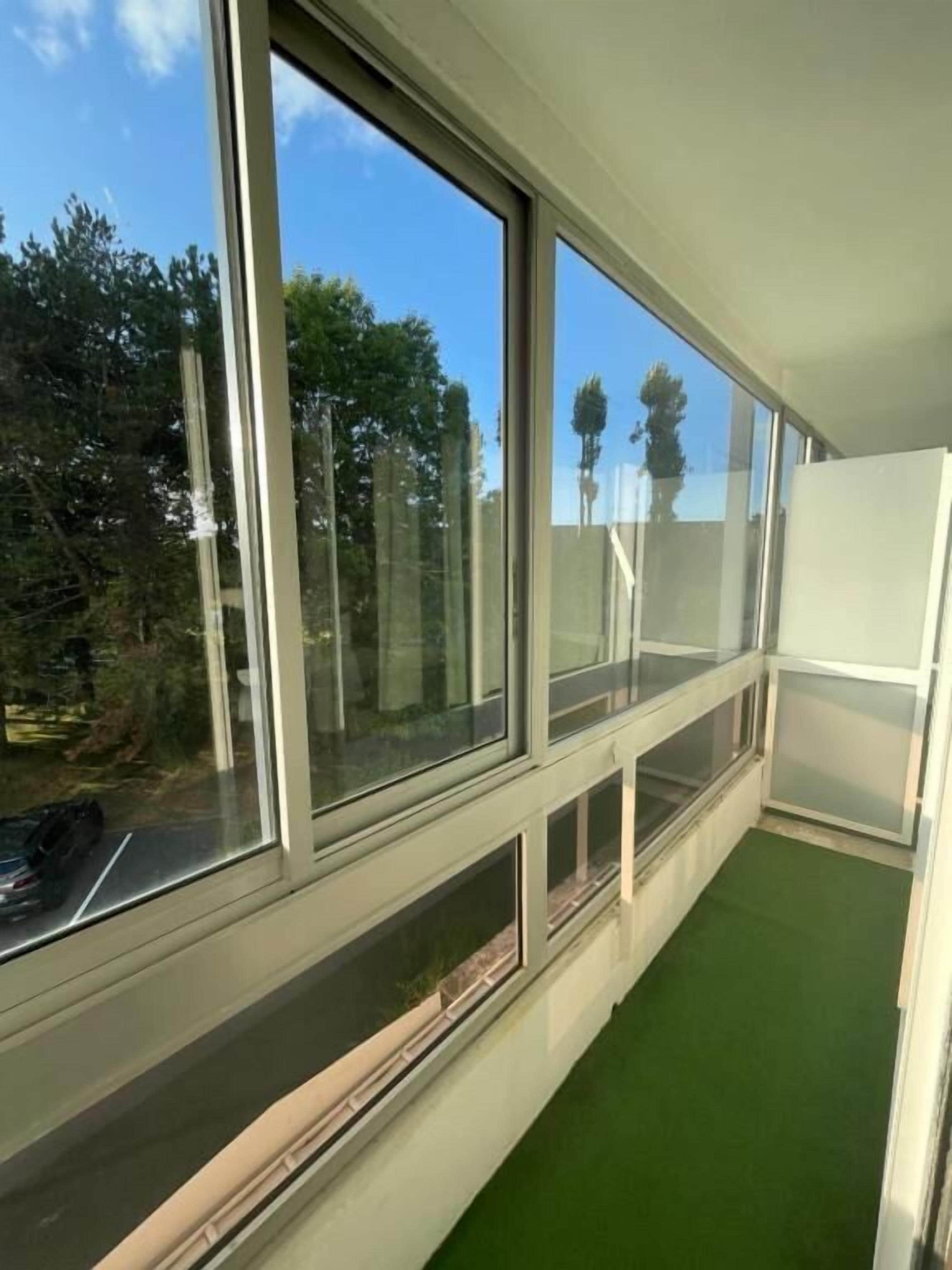 A room with large windows, a green carpet, and a white wall.