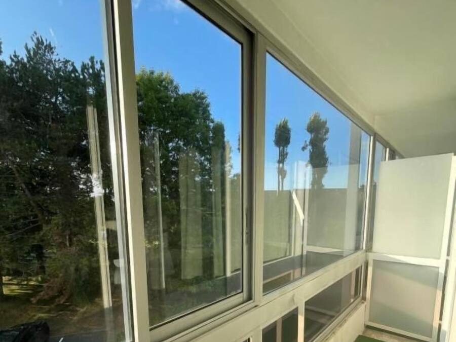 A room with large windows, a green carpet, and a white wall.