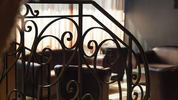 Um interior moderno com guarda-corpo de metal, mobiliário de couro e uma grande janela com persianas.