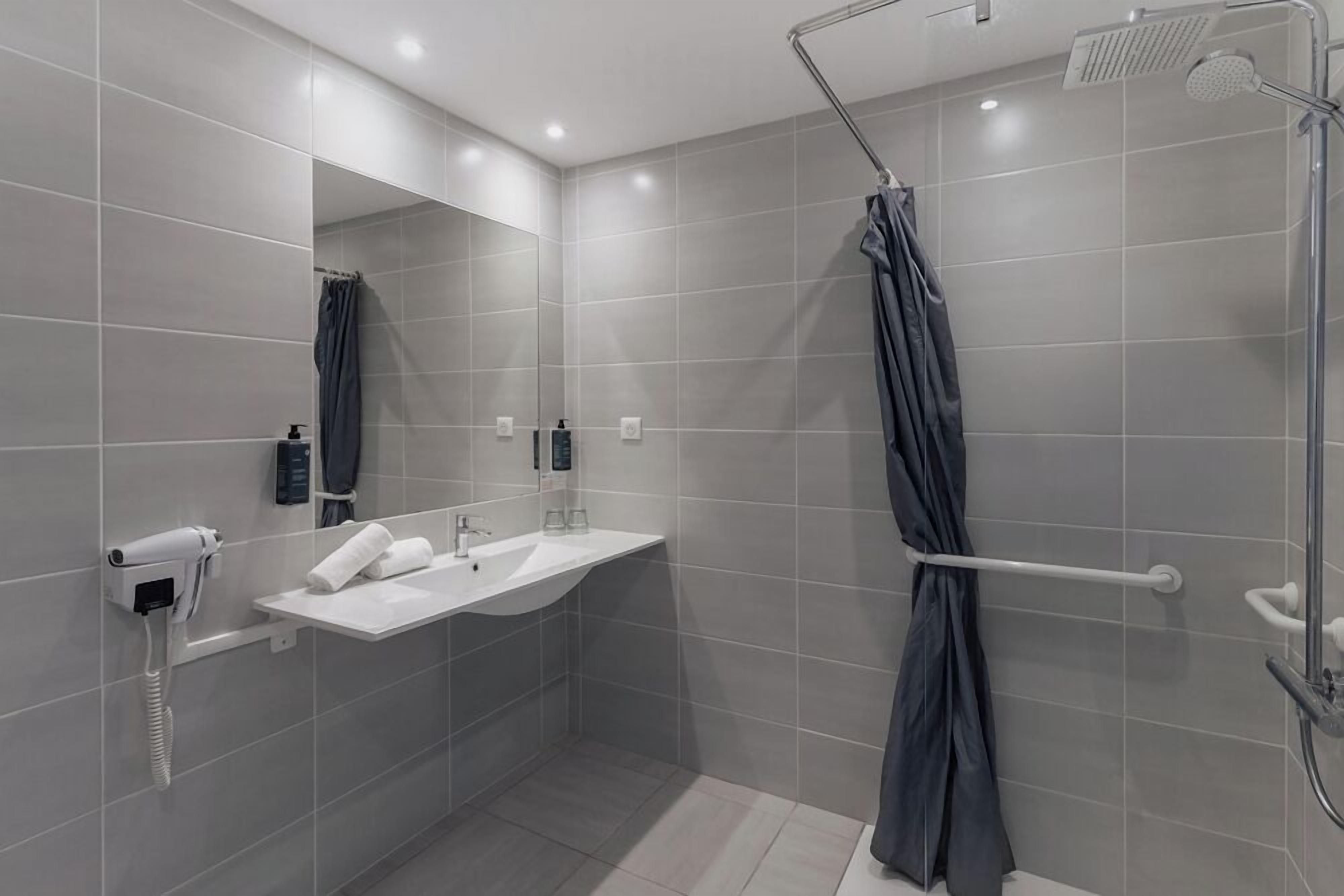 A modern bathroom with a shower, a sink, a mirror, and a towel rack.
