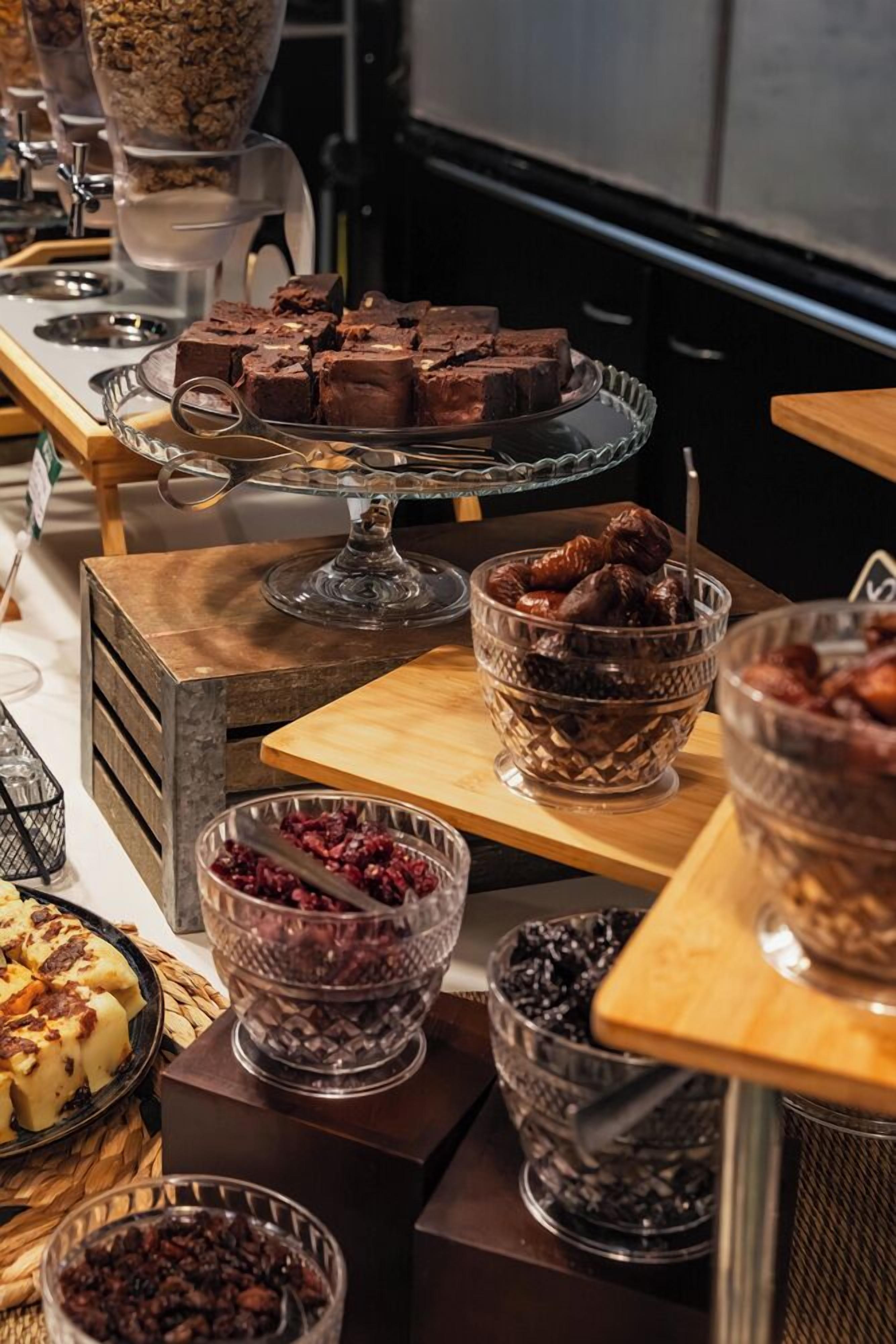 Un bufé con diversas opciones de comida, como brownies, nueces y frutas secas.