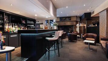 A bar area with stools, a fireplace, and a variety of bottles.
