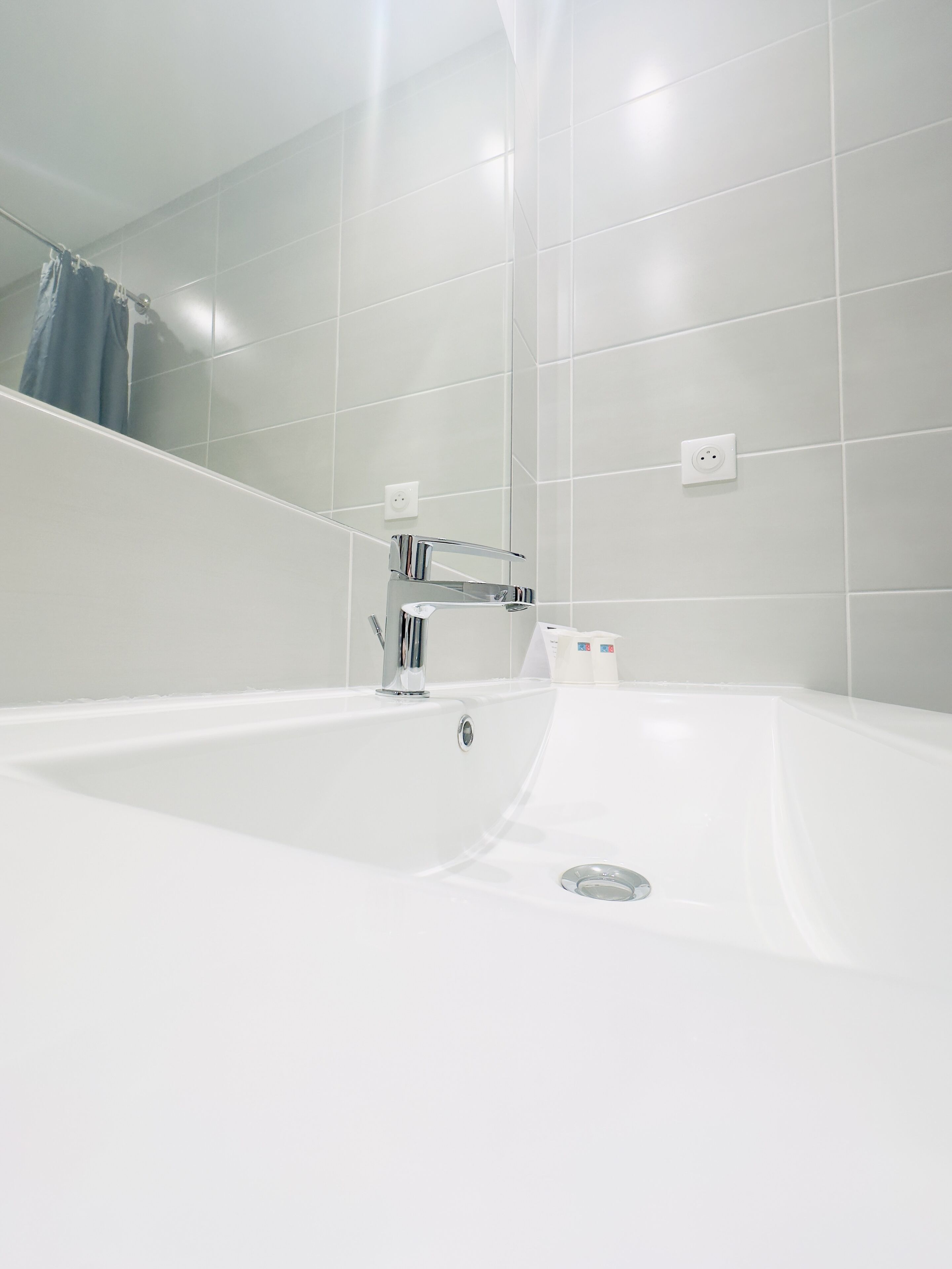 A modern bathroom with a large white bathtub, a chrome faucet, and a mirror.