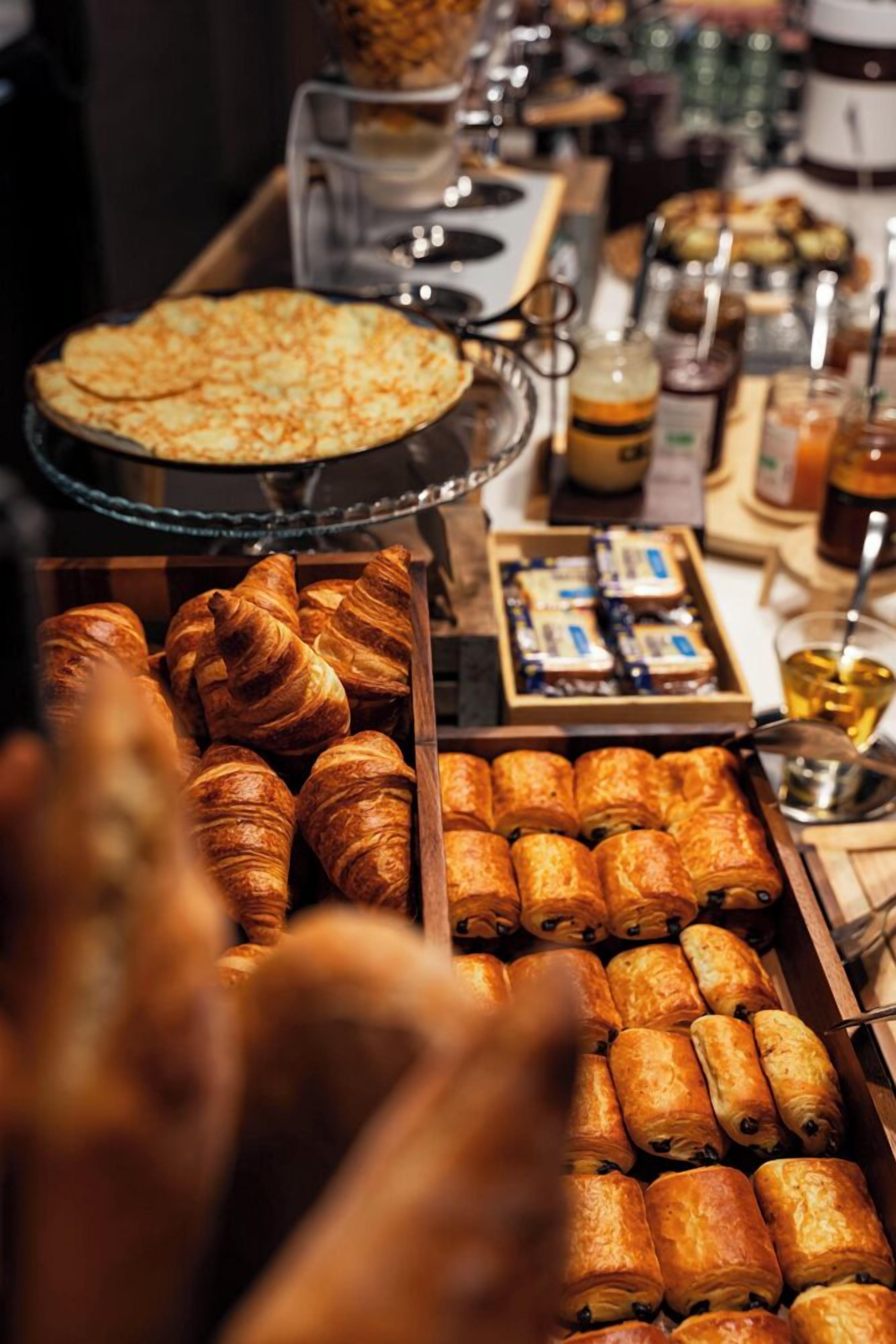 A buffet with various baked goods including croissants and pastries.