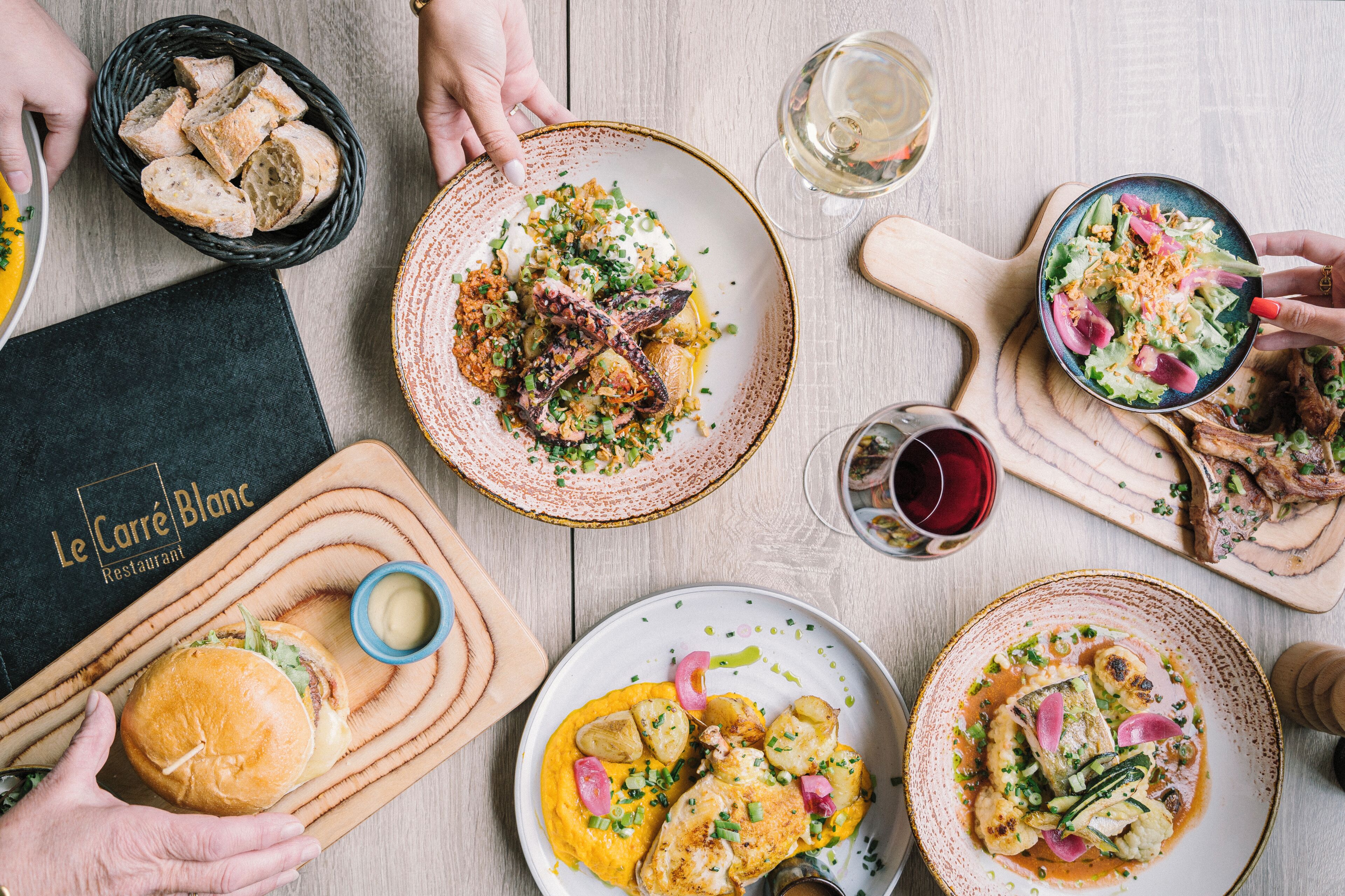 A dining table with various dishes, a menu, and a glass of wine.